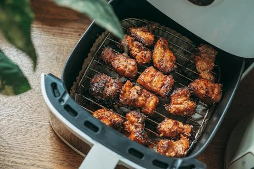 "Air fryer on a kitchen counter with freshly cooked food inside"
