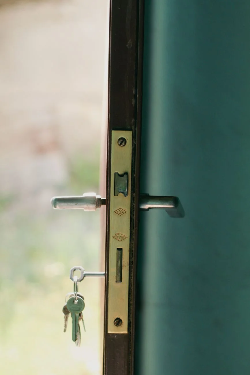 A house key held next to a front door, representing the goal a down payment savings plan is working toward