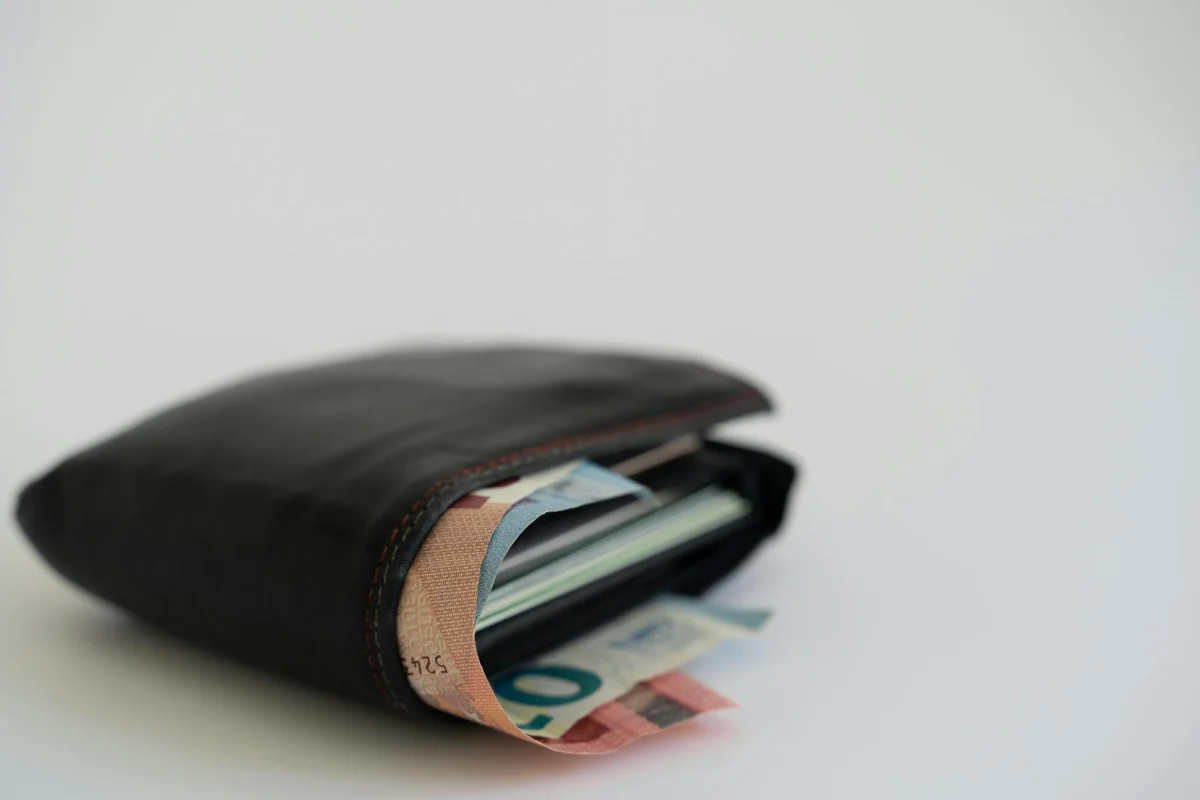 A leather wallet open with cash bills visible