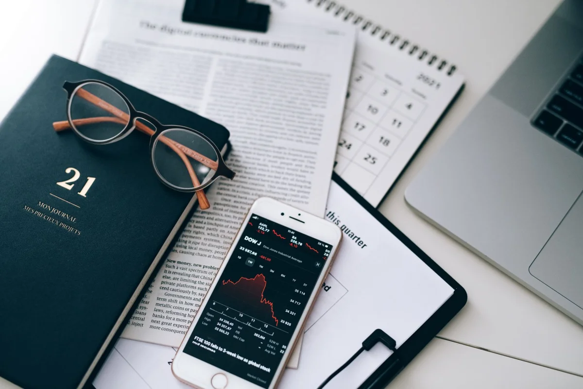 A wall calendar and a pen resting on an open planner next to monthly statements