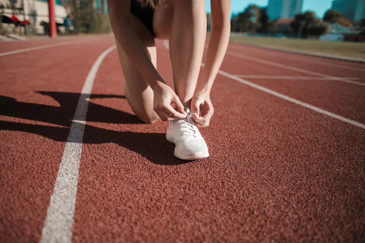 person tying running shoes at the start of an outdoor track