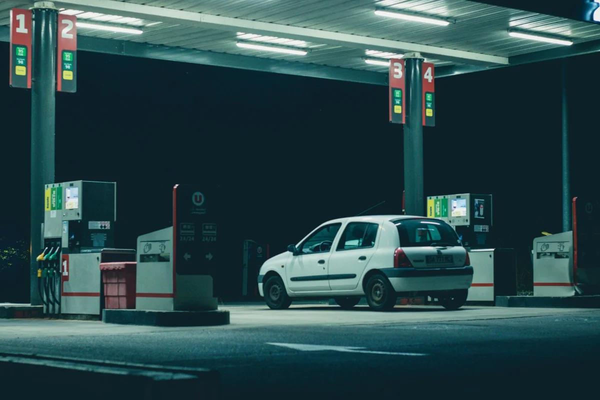 A car being refueled at a gas station pump beside a highway