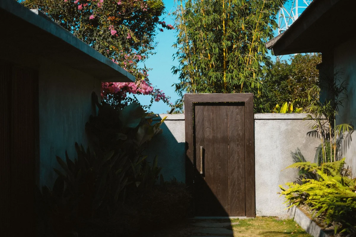 Wooden picket fence running along a sunny backyard lawn