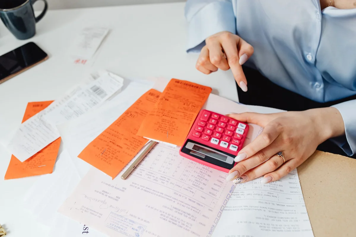 A small business owner reviewing receipts and a calculator at a counter