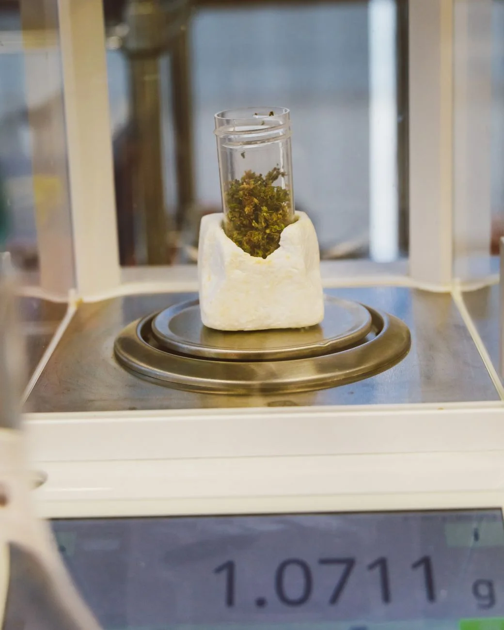 A laboratory balance scale weighing a small metal sample