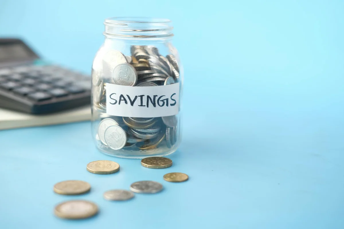 Piggy bank next to coins on a wooden desk