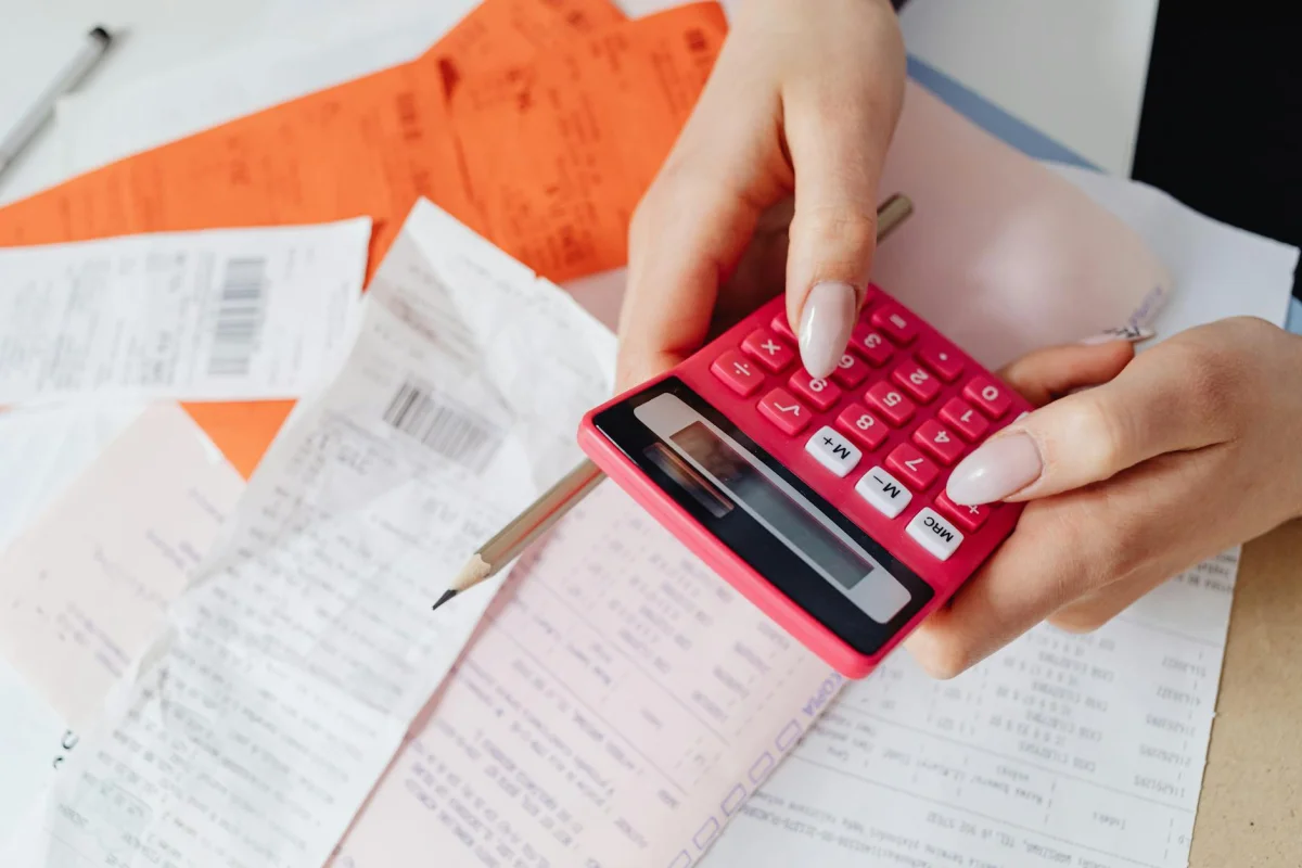 open notebook with handwritten invoice next to a calculator and pen
