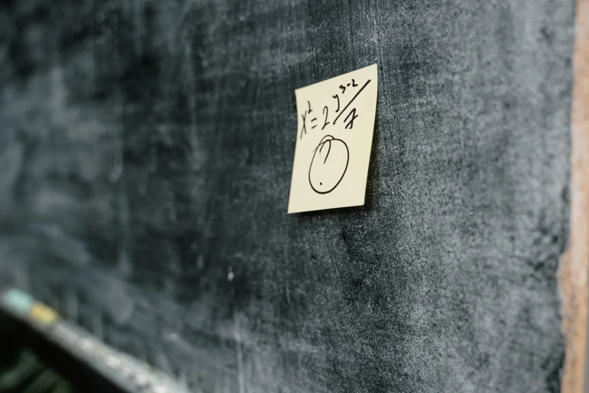 Chalkboard covered in handwritten arithmetic and number lists