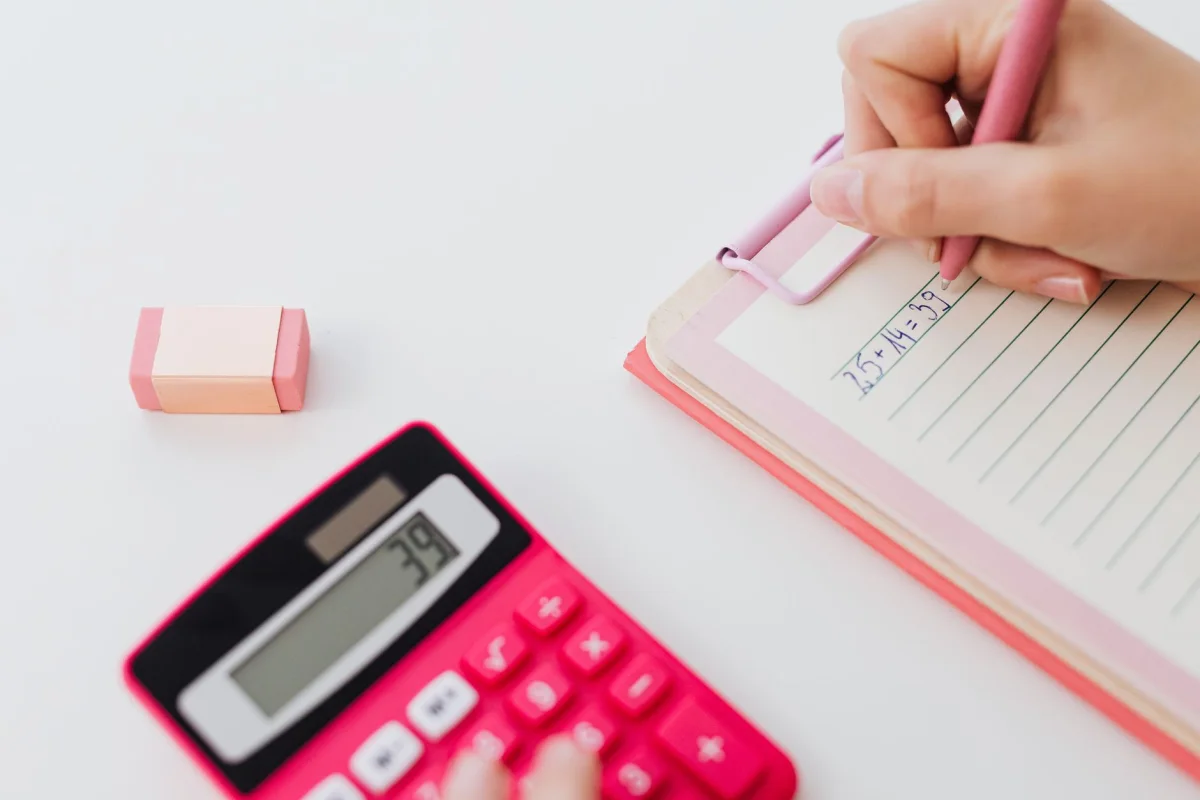 A notebook with handwritten asset and liability columns next to a calculator