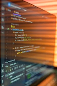 Developer writing code on a laptop screen with syntax highlighting