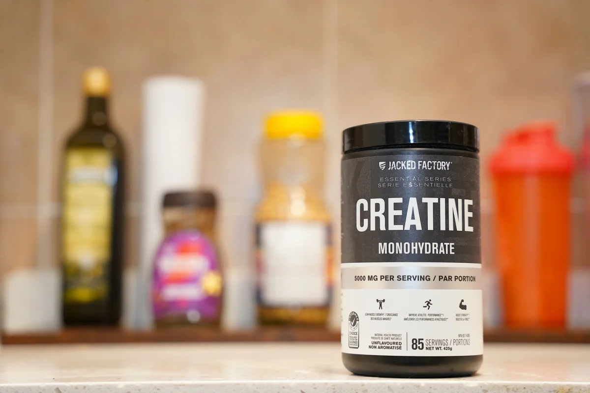 A row of supplement bottles lined up on a kitchen counter in morning light