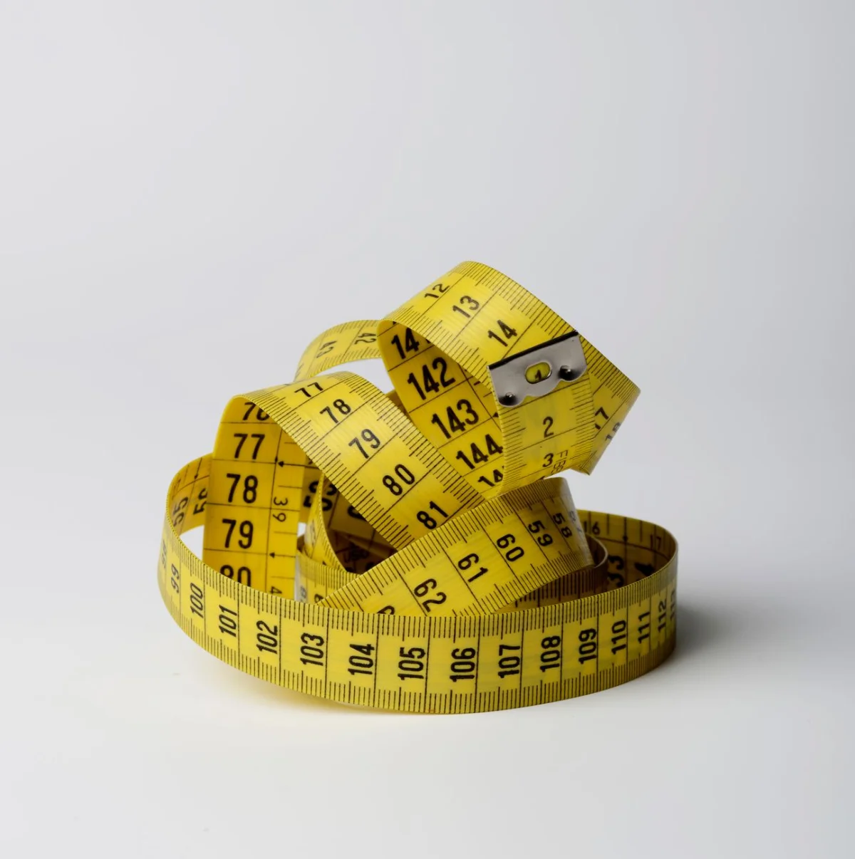 a fitness measuring tape coiled on a gym floor next to free weights