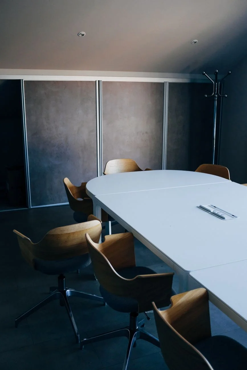An empty conference table with chairs pulled out after a meeting has ended