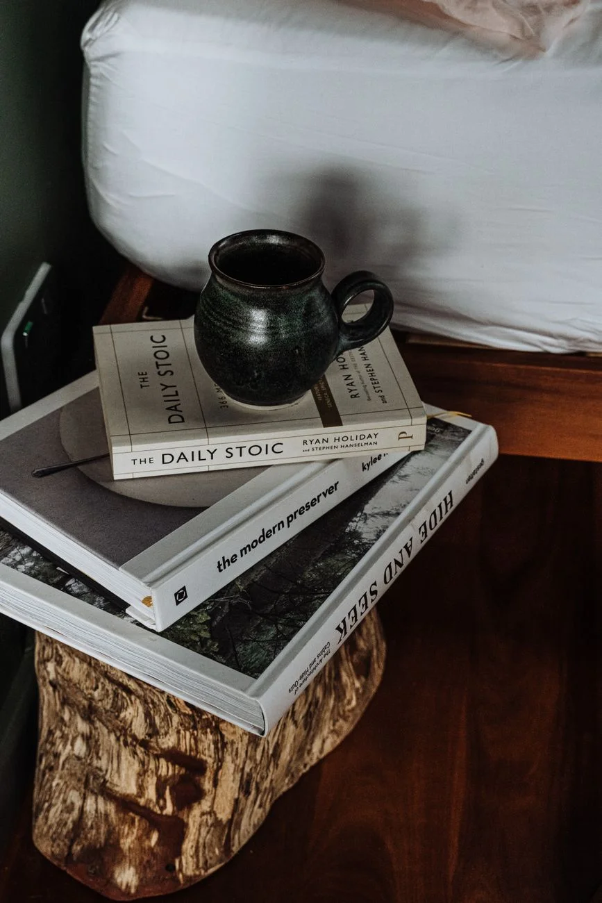 A coffee mug on a bedside table next to a lit lamp in the evening