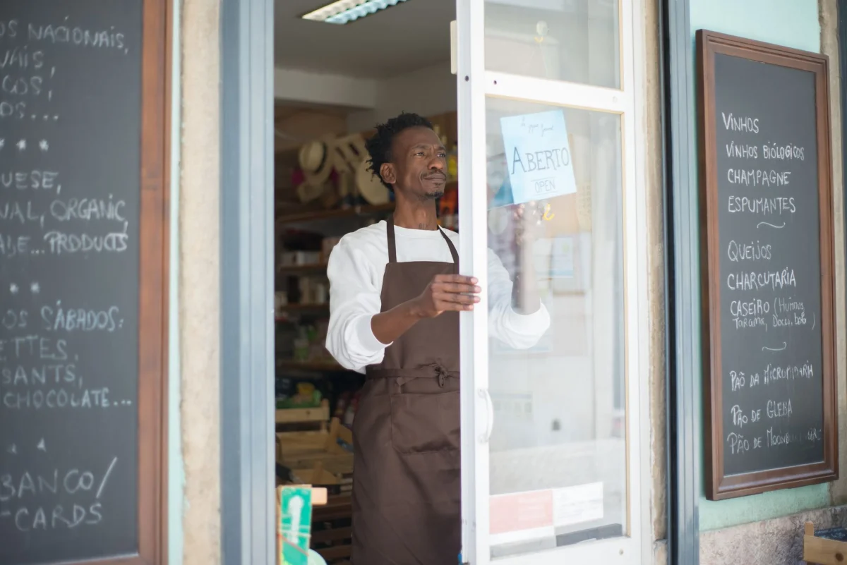 A small business owner standing in their storefront reviewing paperwork