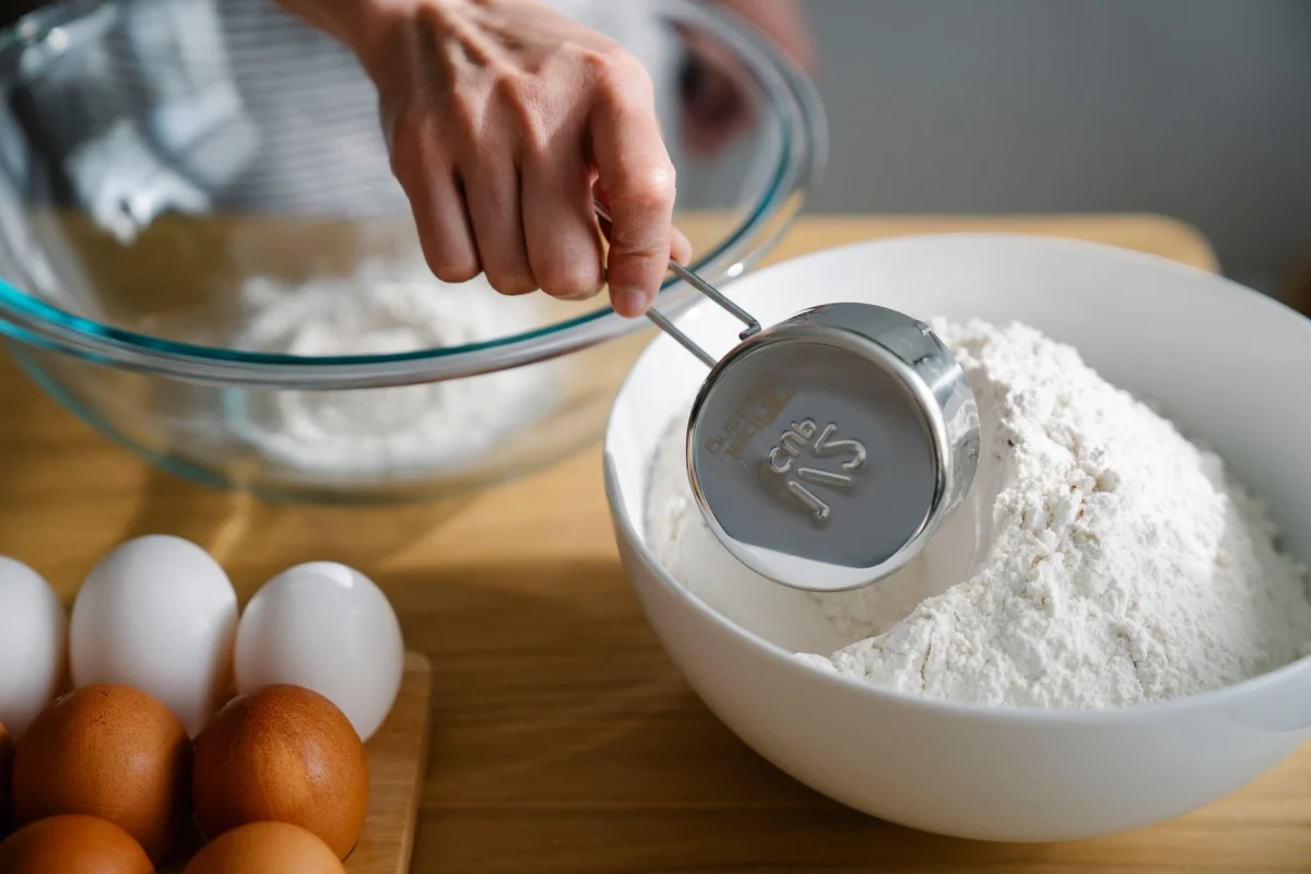 Measuring cups and flour arranged on a kitchen counter for scaling a recipe