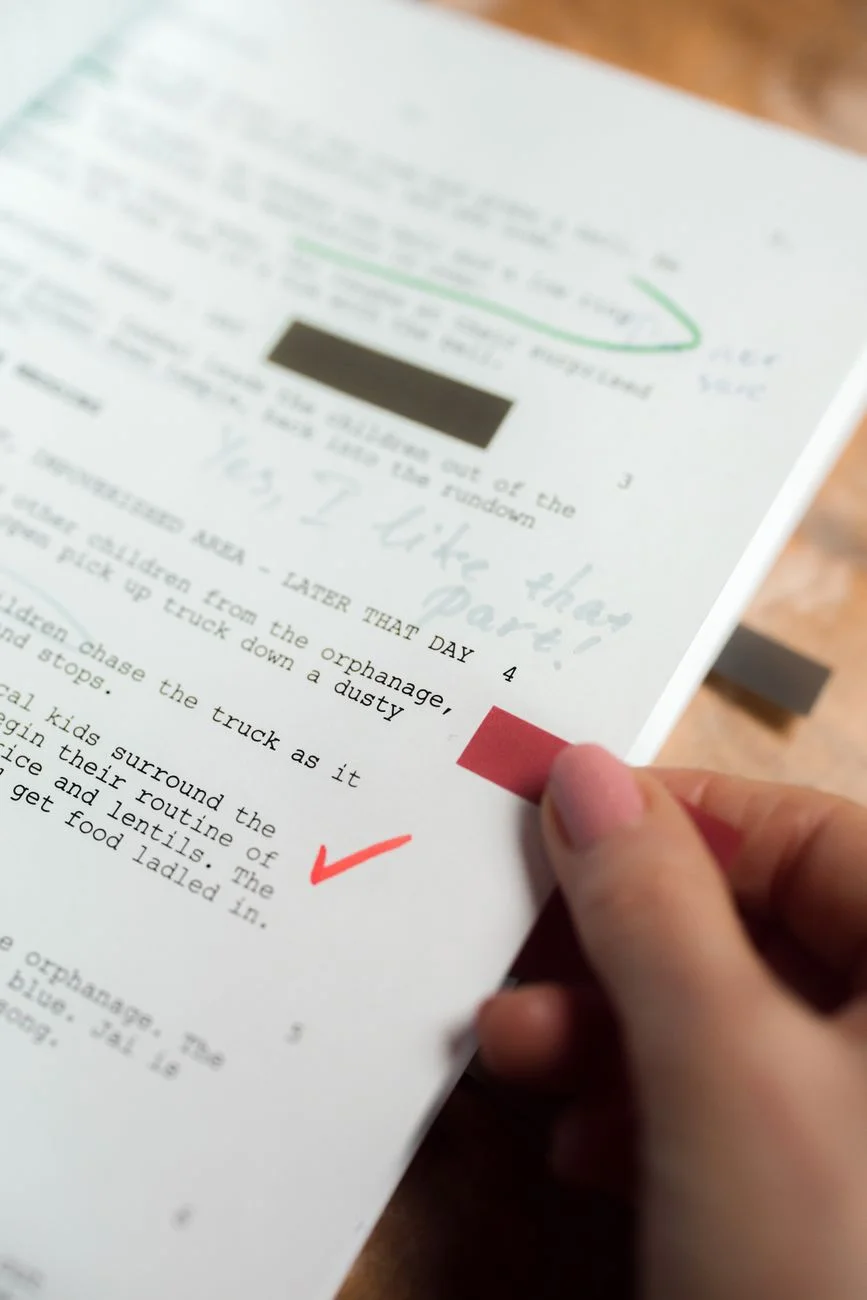 A red pen marking corrections on printed manuscript pages, representing editing and proofreading