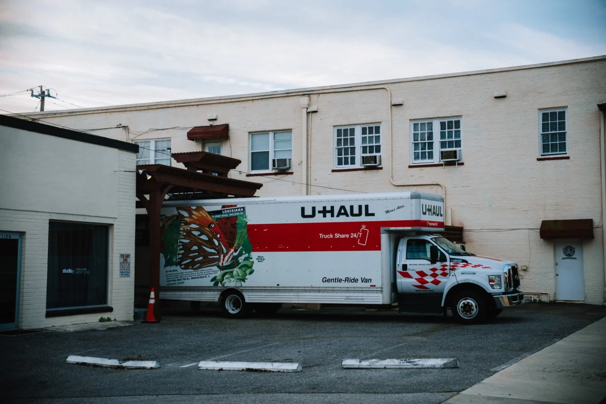 A loaded moving truck parked in a driveway next to stacked cardboard boxes