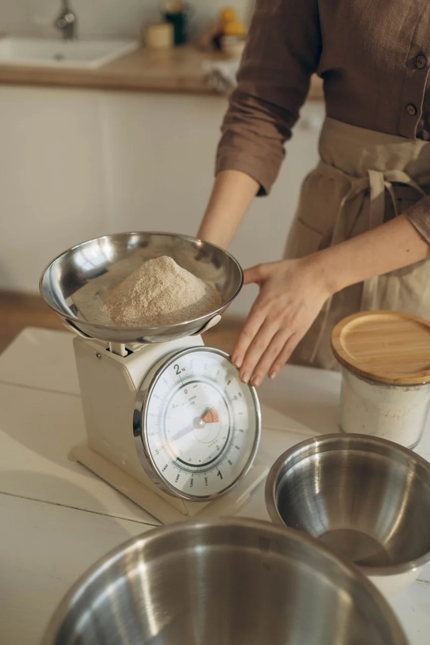 Fresh ingredients being weighed on a kitchen scale next to a recipe card